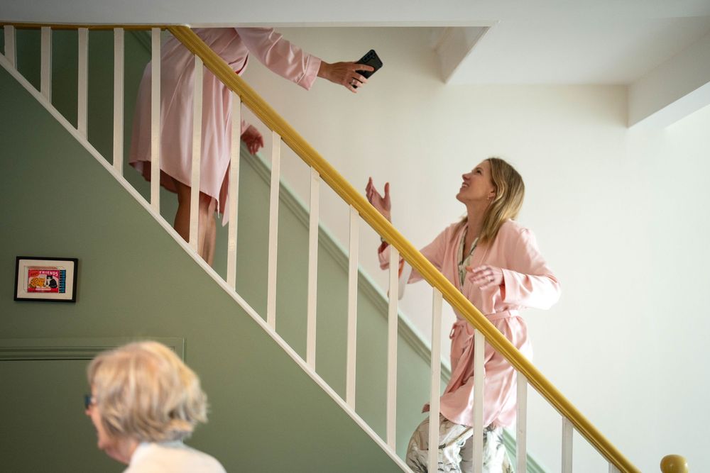 Someone in pink clothing looking up the staircase in a white-walled home.