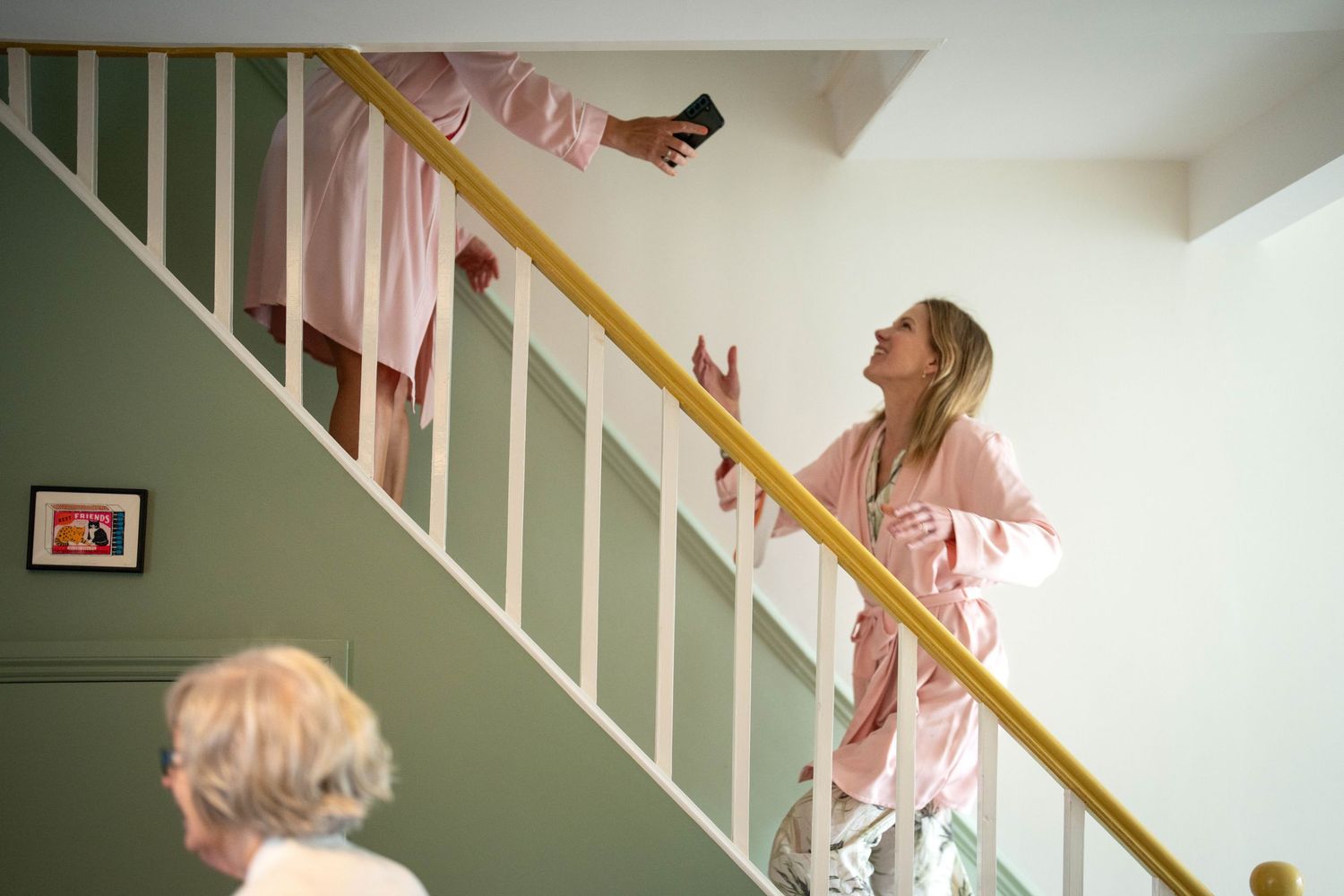 Someone in pink clothing looking up the staircase in a white-walled home.