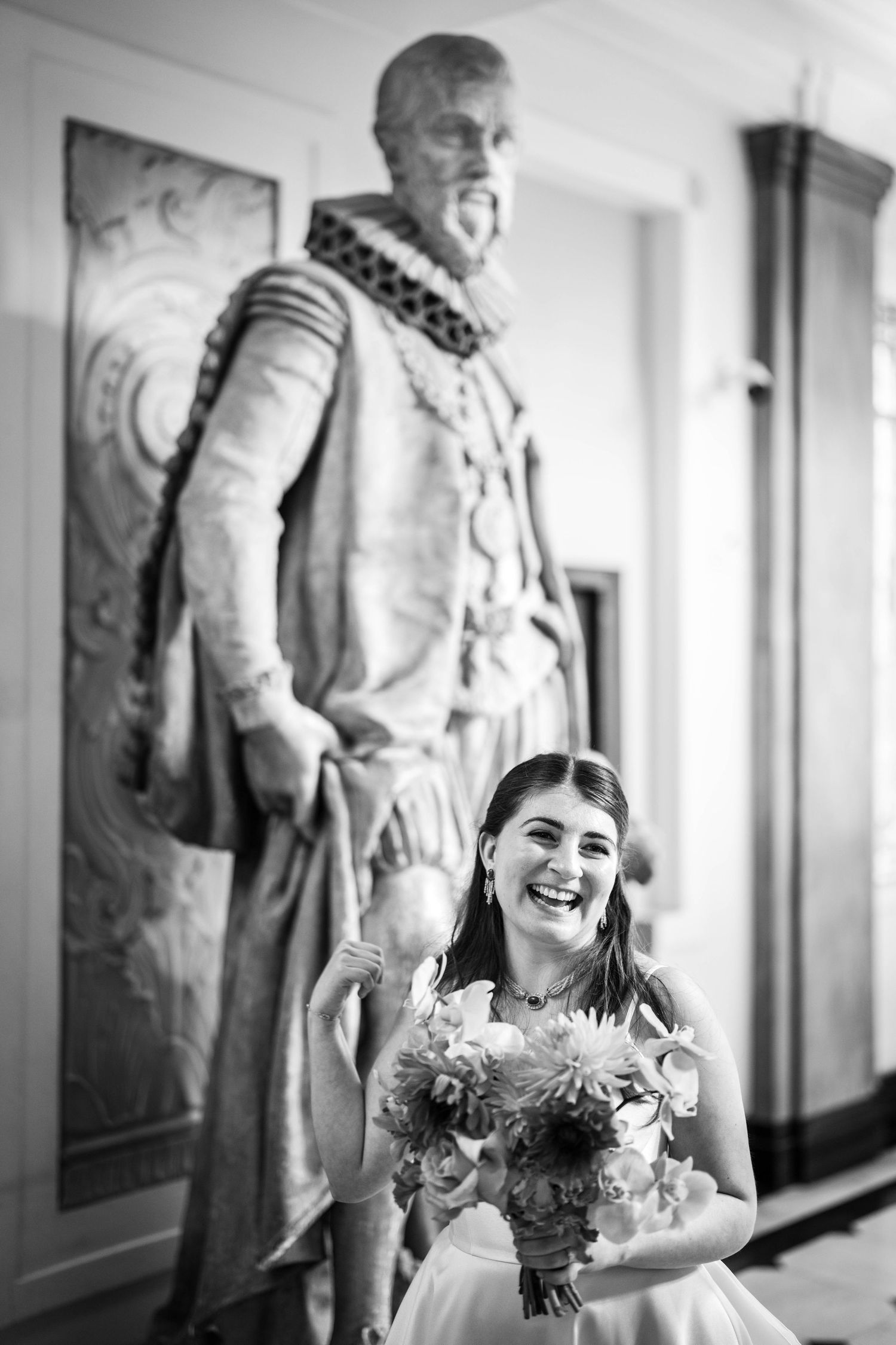 Black and white photo with a statue towering over someone holding a bouquet.