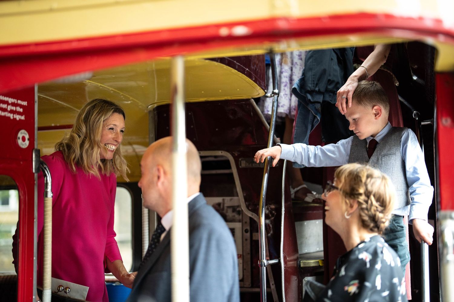 People boarding a bright red bus or transport vehicle.