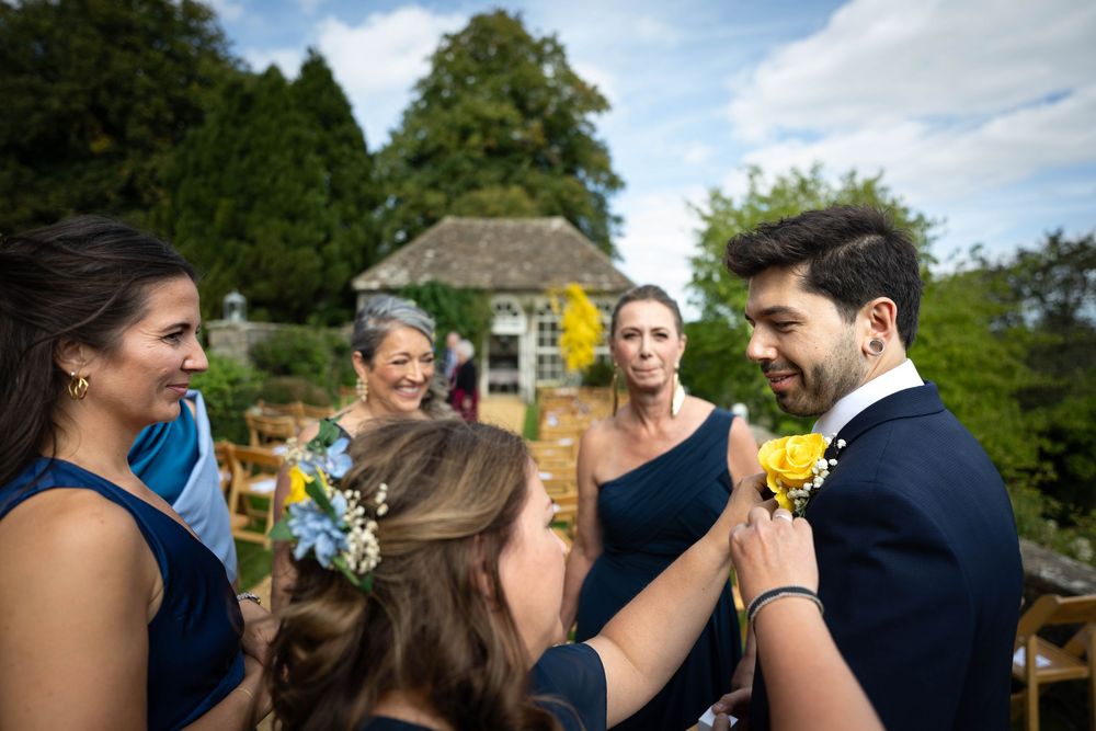 Wedding party gathering in a garden with a gazebo in the background.