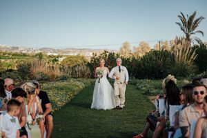Wedding guests celebrate outdoors during sunset on a grassy lawn with mountains visible in the background.