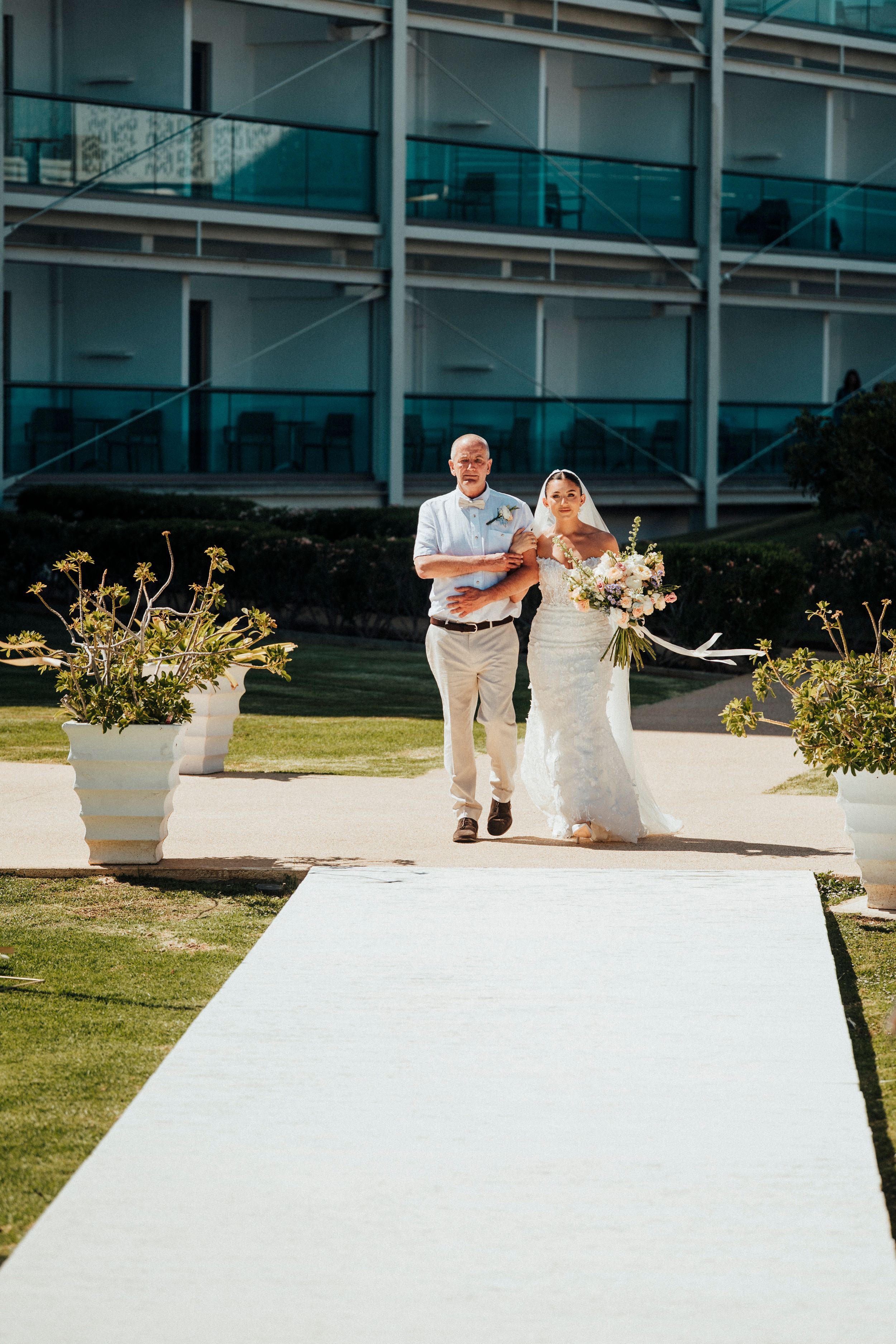 A sequence of wedding photos showing a couple walking behind a white wall with decorative planters in an outdoor setting.