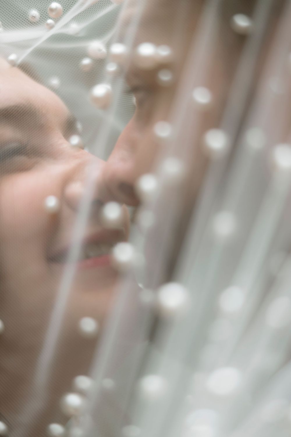 Pearl decorations and delicate tulle fabric create an ethereal wedding detail against a soft blurred background.