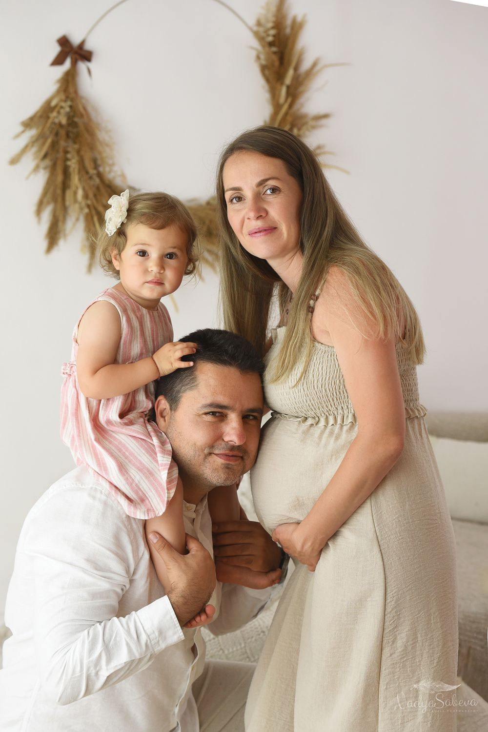 A loving family moment shows a small group sharing tender embraces against a white wall.