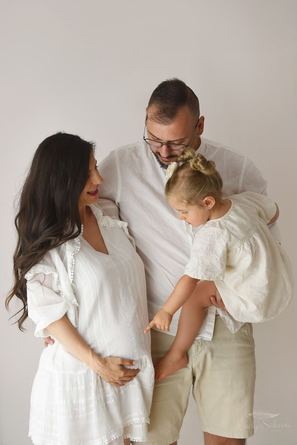 A series of five candid photos of a family in white clothing interacting lovingly against a light gray background.