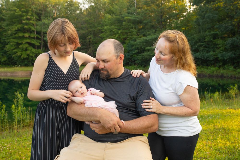 A tender family moment outdoors as they gather around a newborn baby.