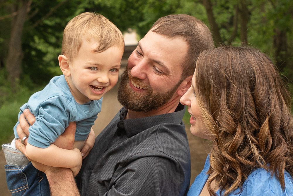 A joyful family moment captured outdoors with natural greenery in the background.