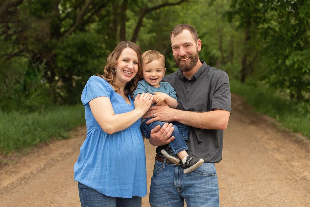 Family shares laughs and hugs on a dirt path surrounded by green foliage.