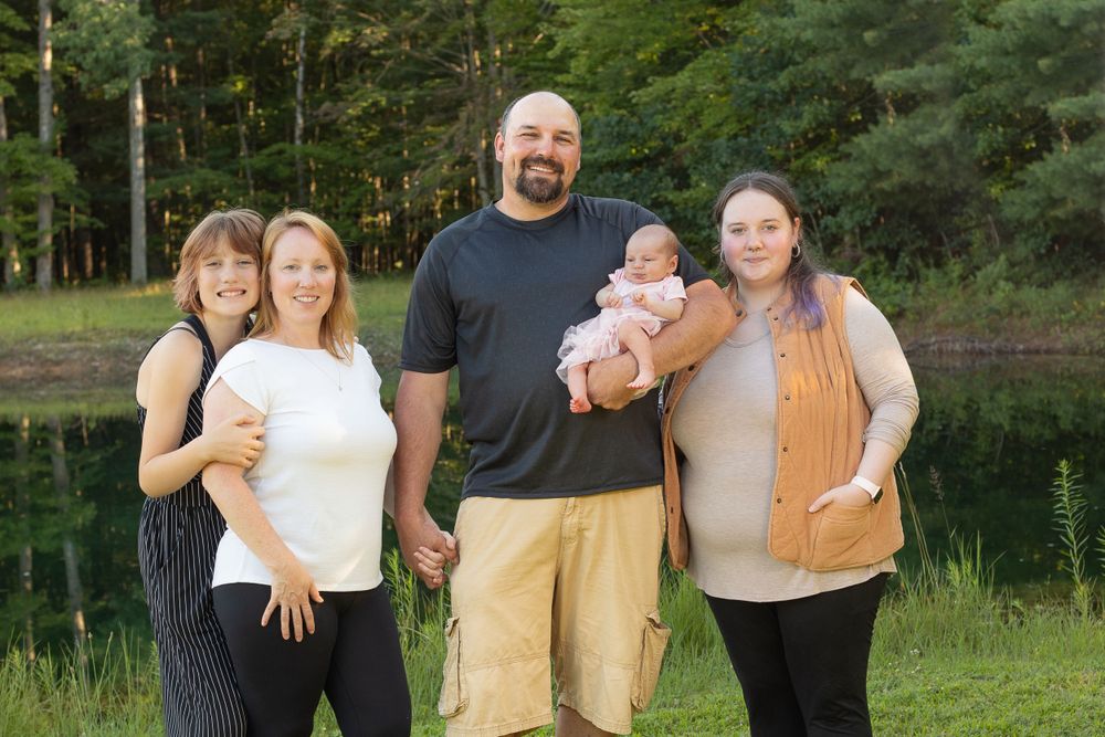 Extended family portrait in a lush green setting with trees in the background.