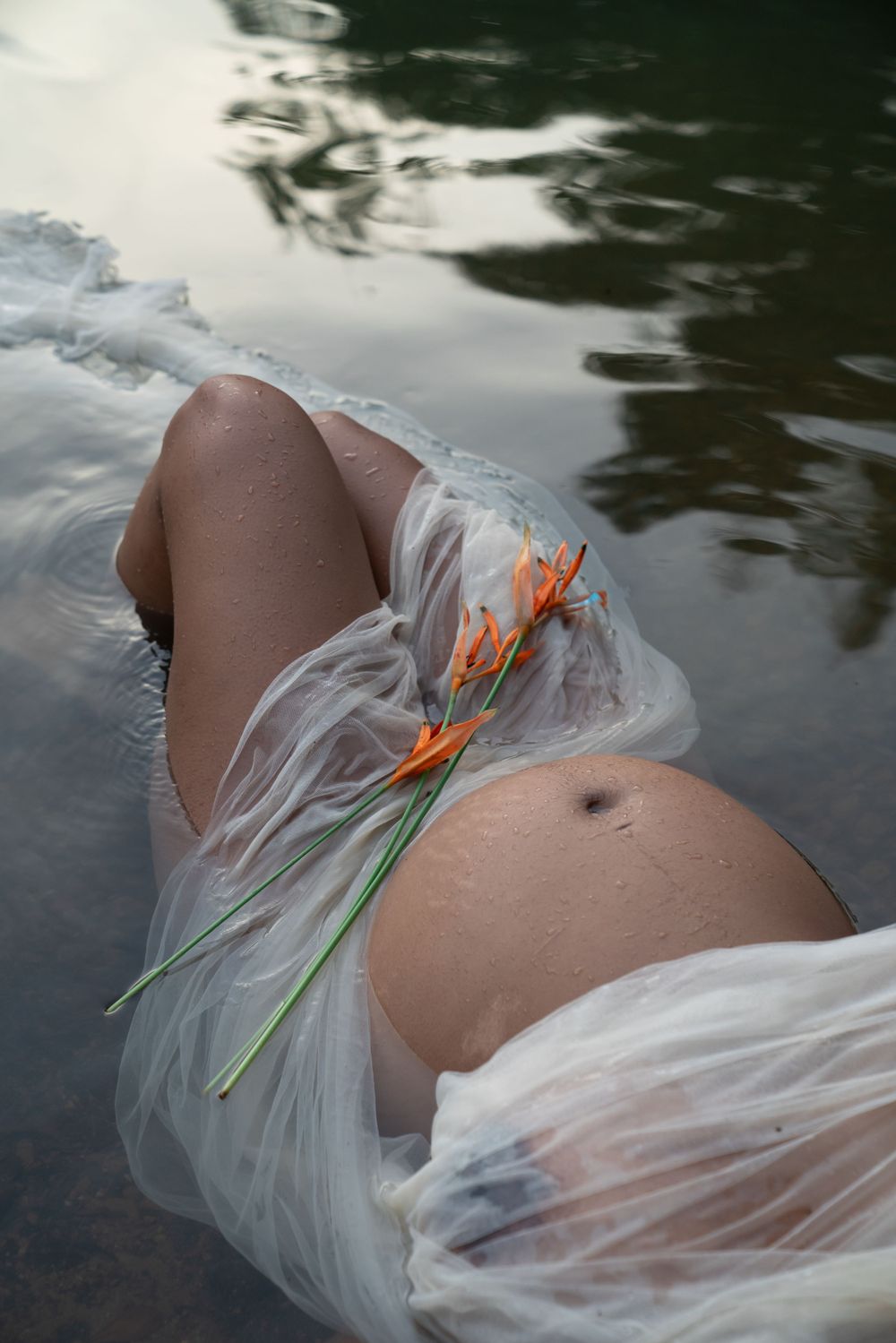 Femme enceinte allongée dans l'eau, shooting grossesse en Guyane