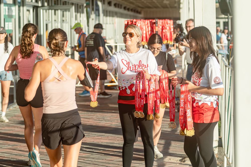 Community 5K run of runners at finish line of Shipley Donut Dash 5K race in Houston TX