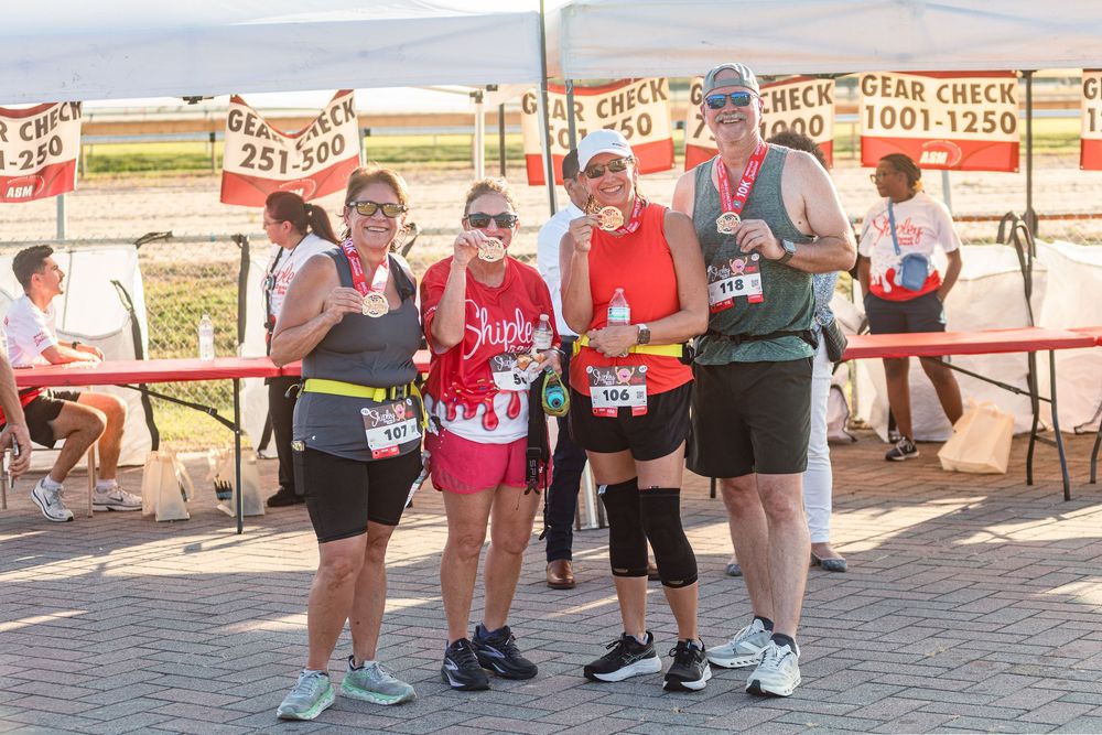 Community 5K run photography in Houston capturing finish line moments small group of runners posing at the Shipley Donut Dash 5K Houston TX