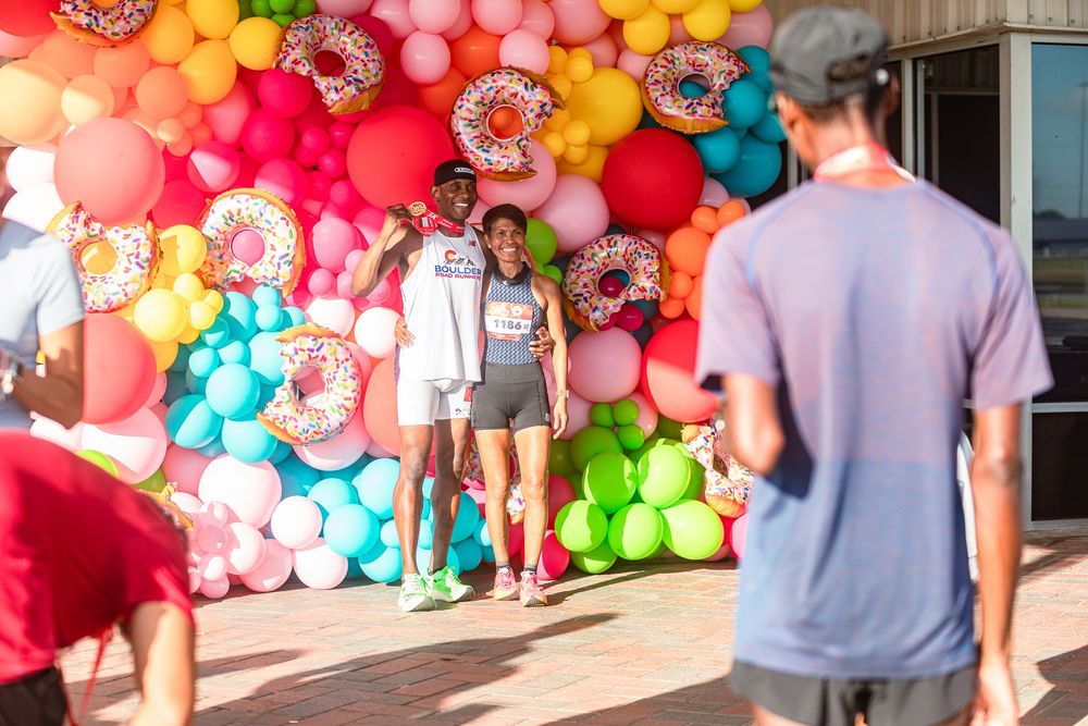 Community 5K run photography in Houston capturing finish line moment. runners wearing medals at the Shipley Donut Dash 5K in Houston TX