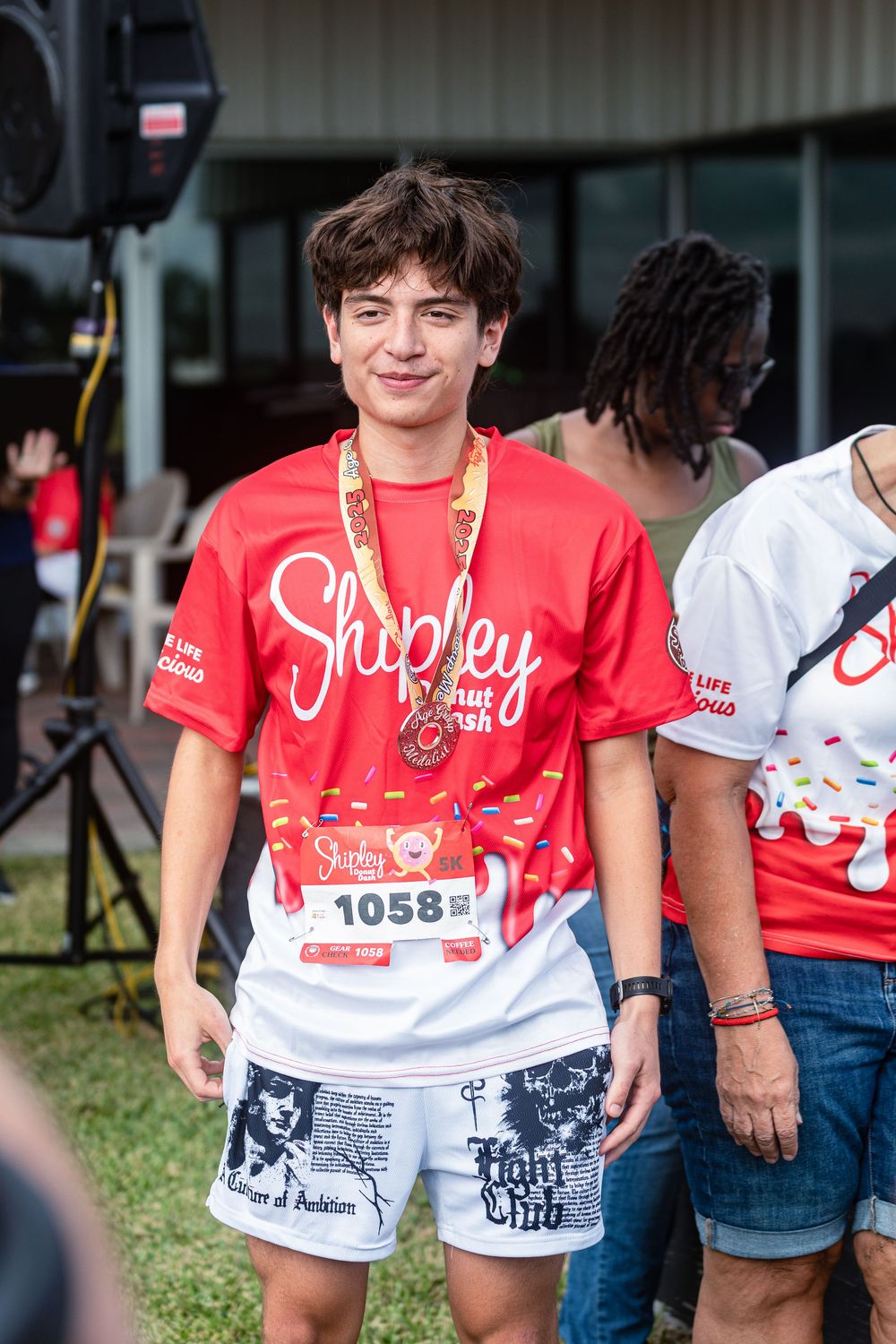 Community 5K run photography in Houston capturing finish line moments. runners wearing medals at the Shipley Donut Dash 5K in Houston TX