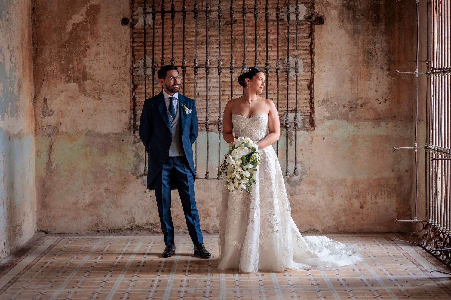 Wedding couple photographed in historic stone corridor with iron gates.