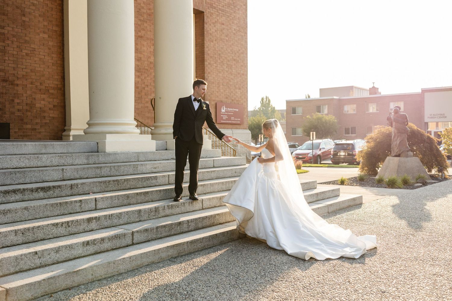 Bride and groom sharing a romantic kiss on a waterfront terrace at golden hour by a serene lake.