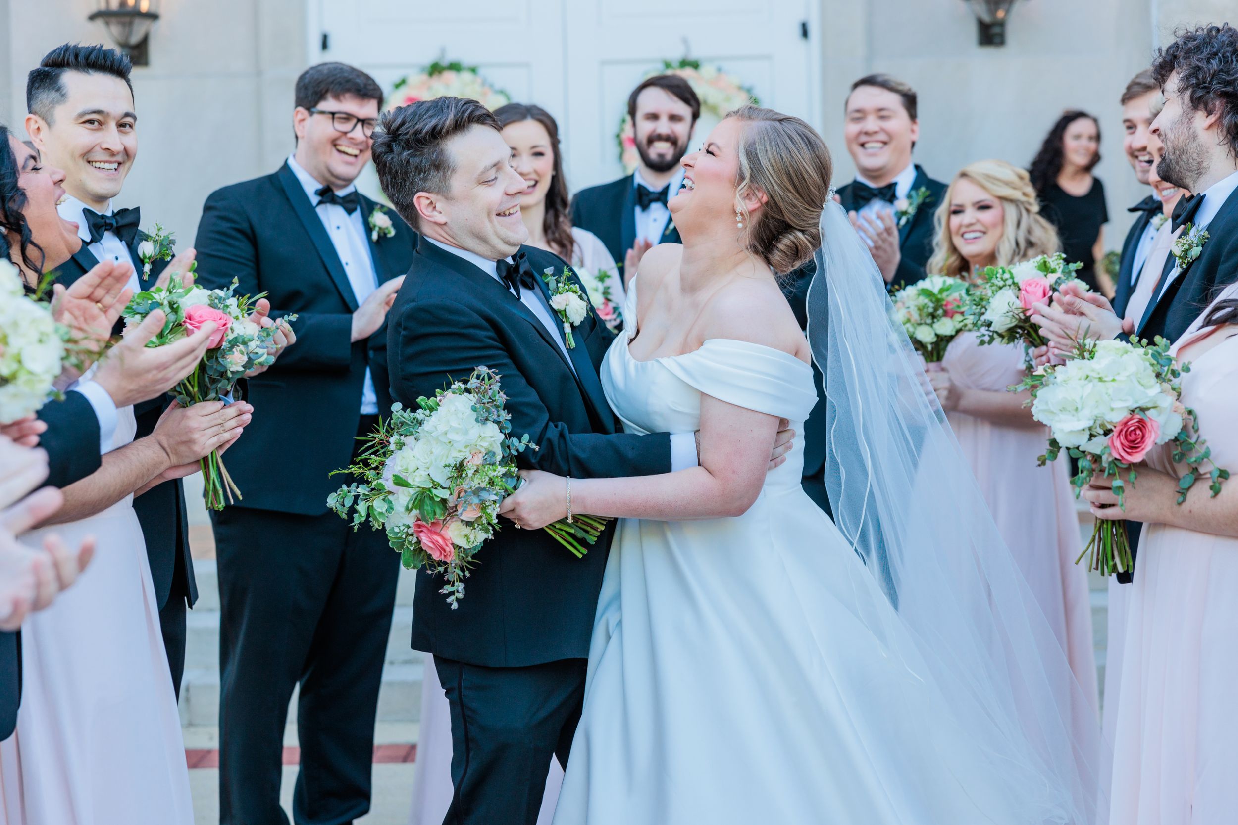 Wedding party celebrates with flowers and laughter during outdoor ceremony.