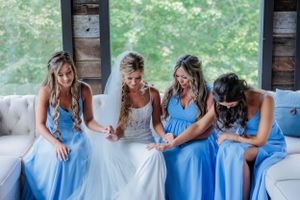 Wedding party in coordinated blue dresses sitting together on a rustic porch.