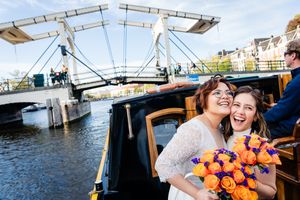 Two brides share a hug and a laugh during a boat ride on their wedding day.