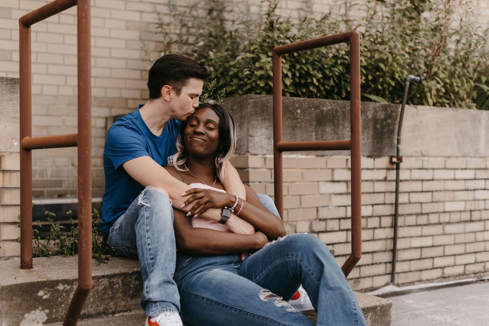Black and white photography portrait of a diverse couple sharing a candid moment kissing on a downtown Akron, Ohio rooftop.