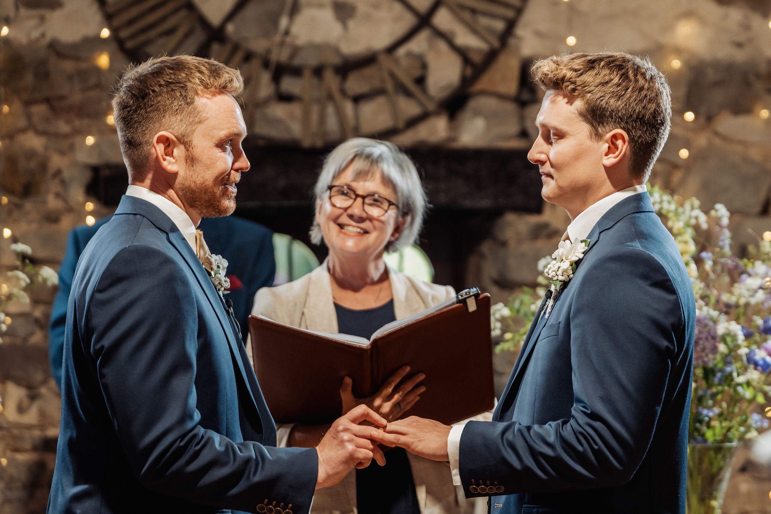 Wedding ceremony moment with officiant holding book in rustic stone setting.