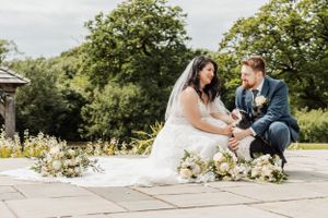 Couple sitting together on stone patio surrounded by delicate white flowers.