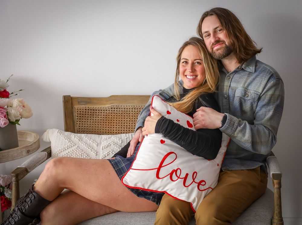 Lifestyle couple photography session with casual indoor setting and decorative pillows.