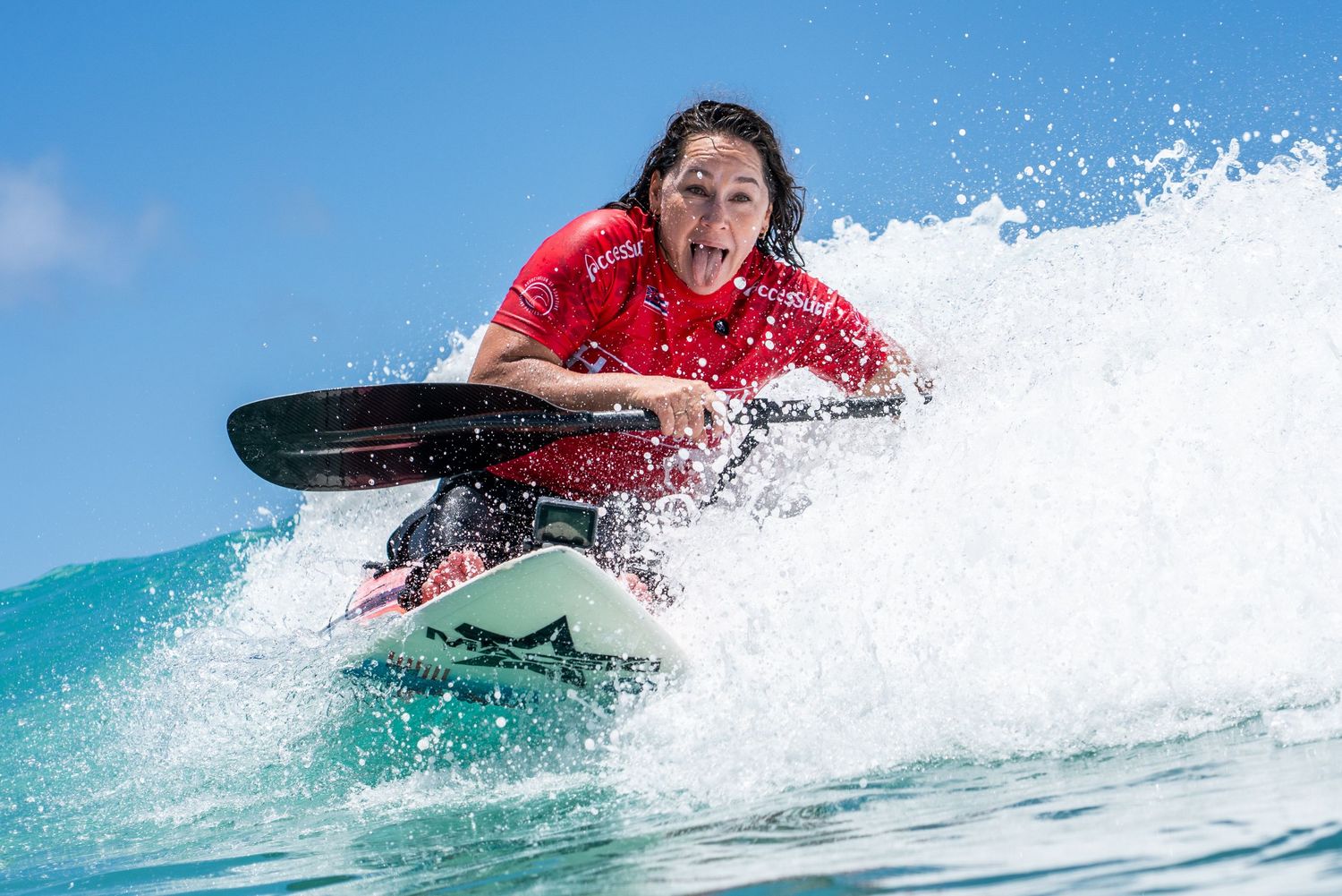 Surfer, Alana Nichols, rides a breaking wave while performing a dynamic surf maneuver.