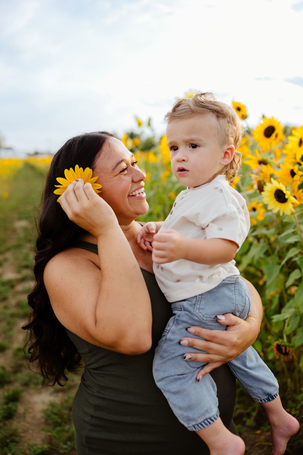 NJ maternity photographer captures pregnant mom and toddler boy posing with sunflowers at jersey acres in medford, nj in south jersey.