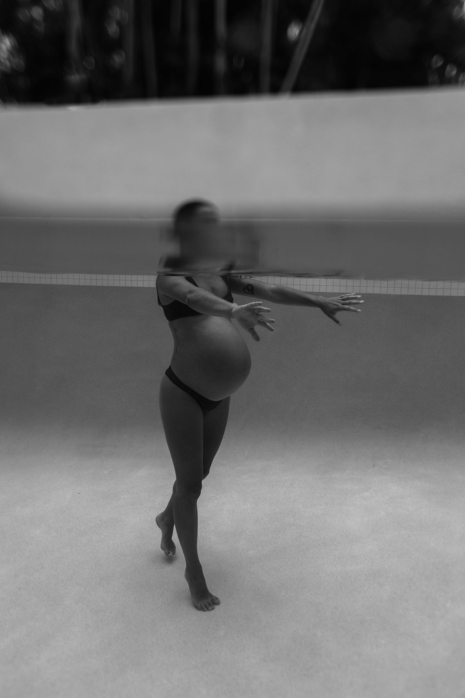 A dancer in a leotard performs a graceful pose on a dance floor in black and white photography.