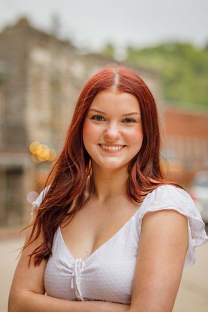 Five photos in sequence showing someone with red hair wearing a white top outdoors against stone architecture.