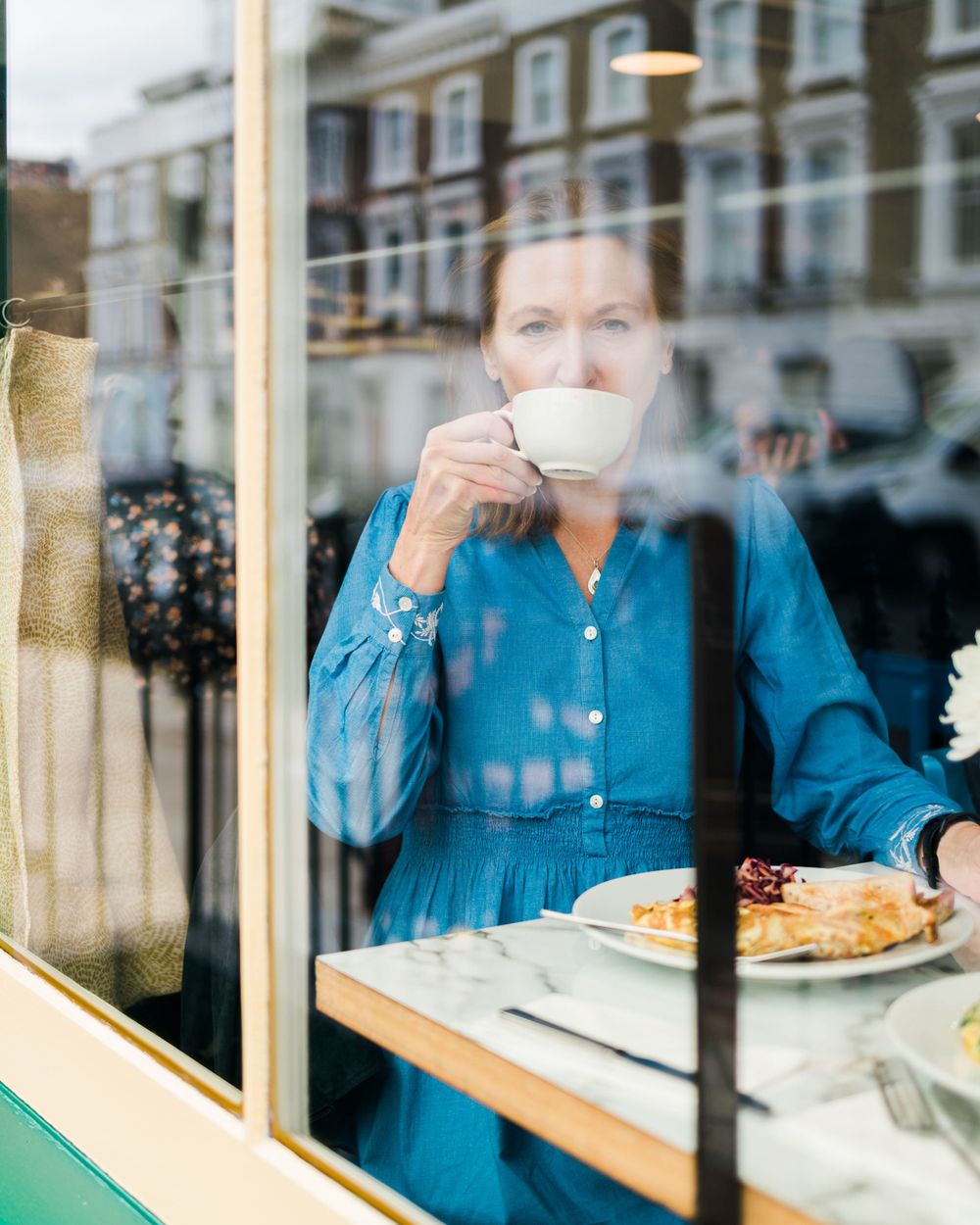 A sequence of five connected images showing someone in blue eating at a window counter of a cafe.