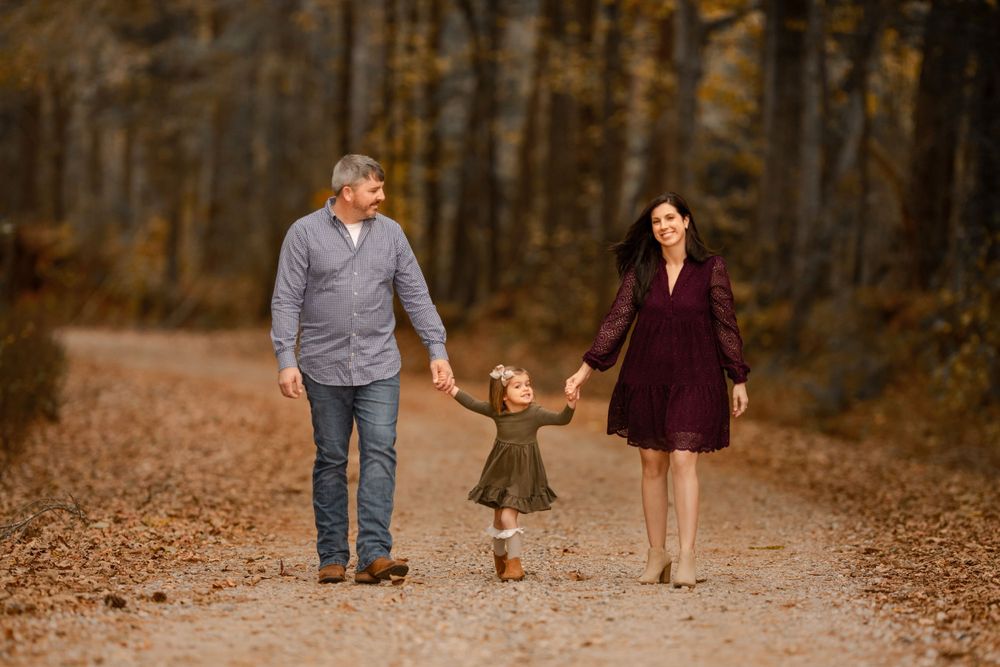 A group walking together on a leaf-covered path through an autumnal forest.