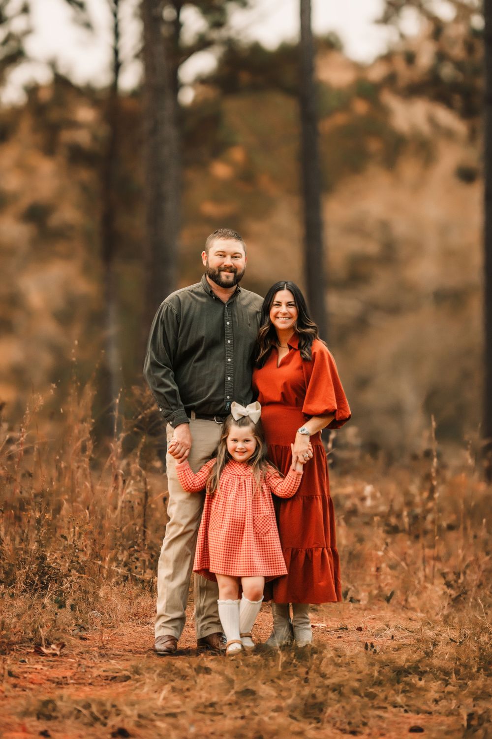A family standing together in a field of tall grass during golden hour.