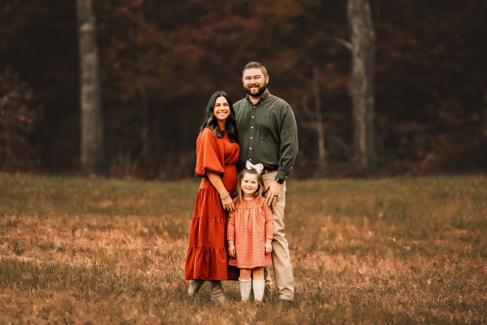 An autumn family portrait with warm tones and coordinated orange and green outfits.