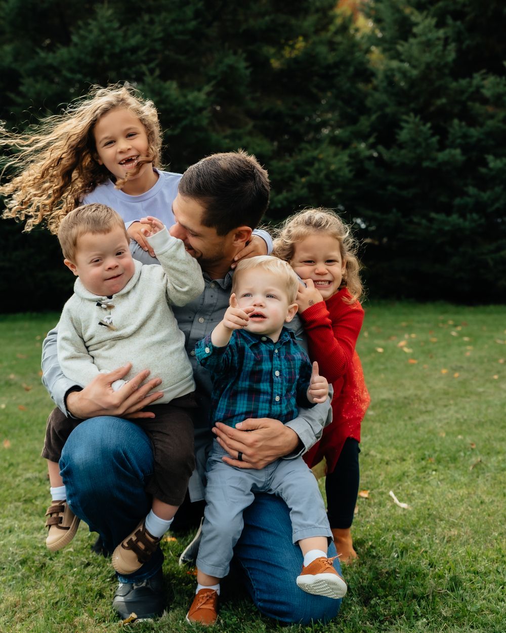 A playful outdoor family moment captured on a grassy lawn during golden hour.