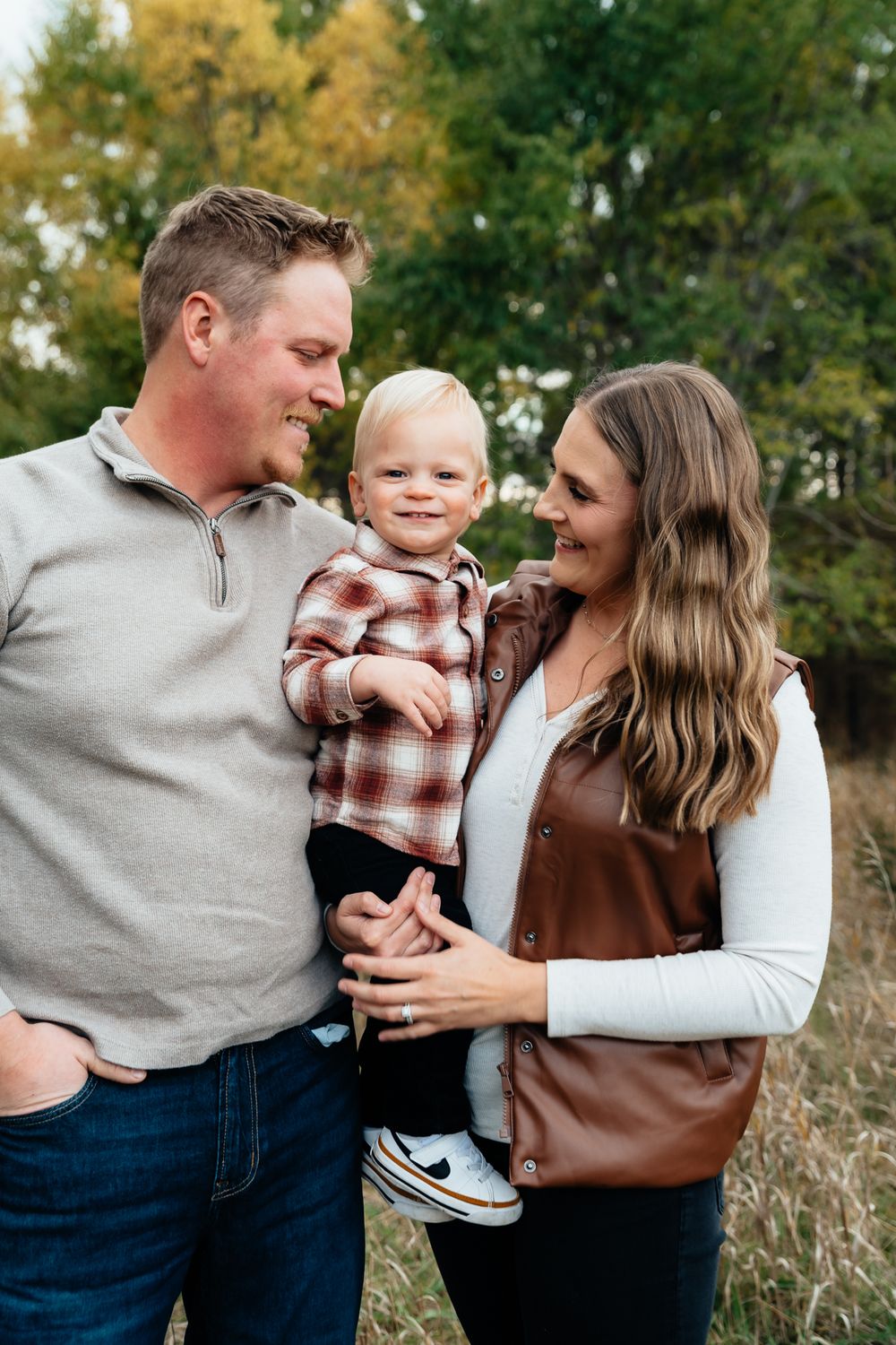 A family shares playful moments together during a fall outdoor photo session.
