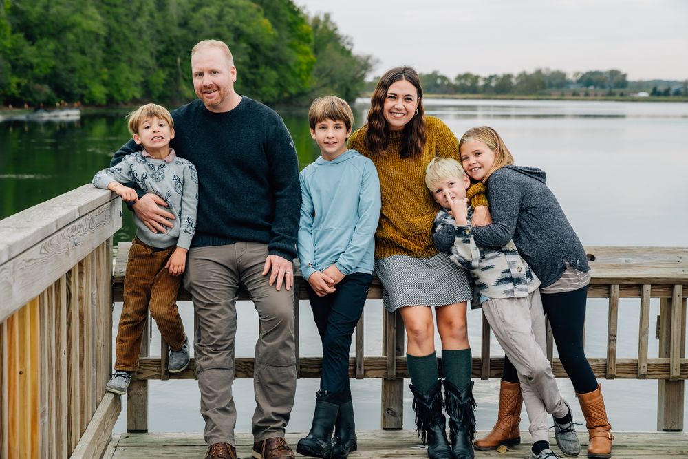 A group poses casually on a lakeside dock during an outdoor family photo session.