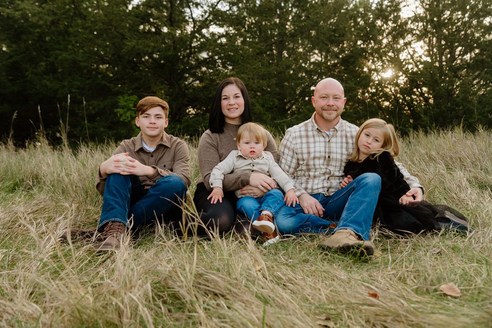 People sit together on grass during a golden hour outdoor photography session.