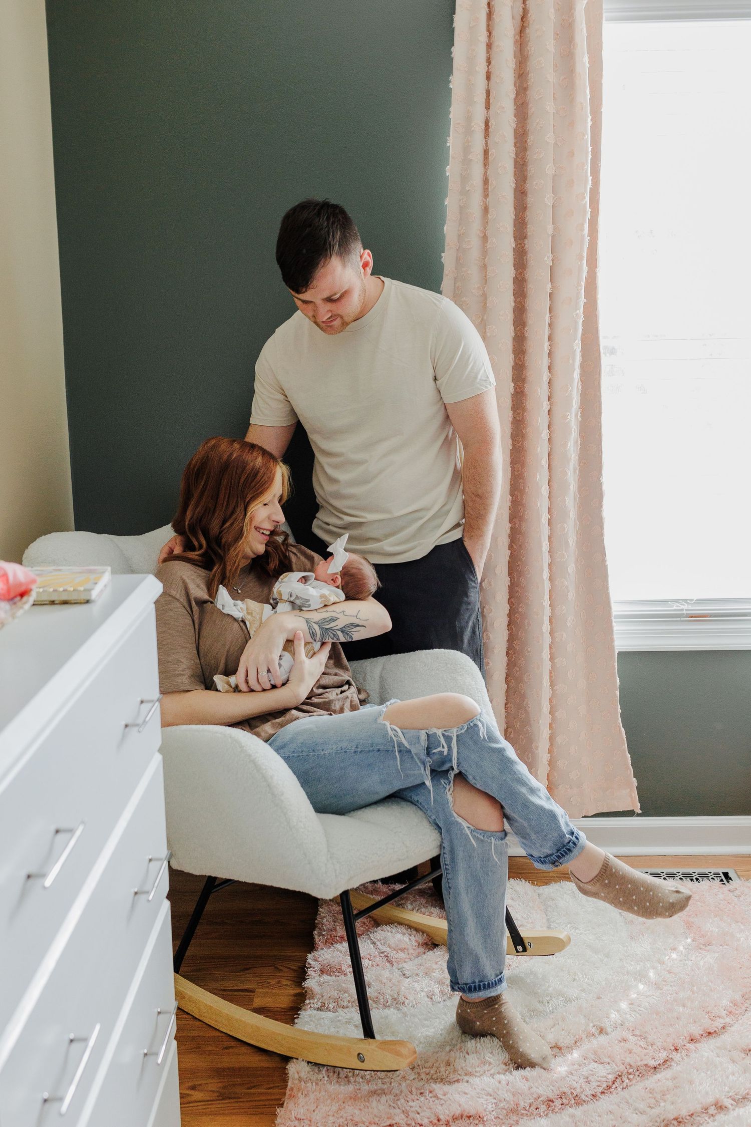 New parents lovingly cradle their newborn baby in a cozy bedroom setting.