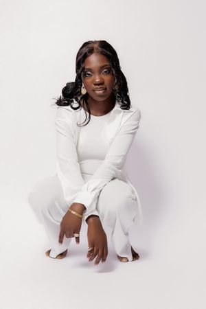 Professional portrait in all-white outfit against light background.