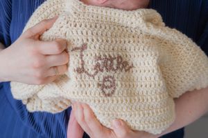 Close up of a hand knitted cardigan with babies name on the back.