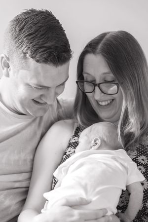 Black and whote, young couple gazing down at newborn baby.