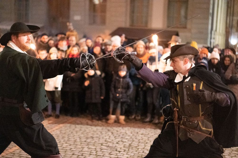 Two performers engage in dramatic sword fight during historical reenactment.