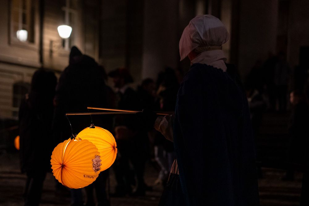 Illuminated yellow paper lanterns glow against dark cathedral walls during an evening celebration.