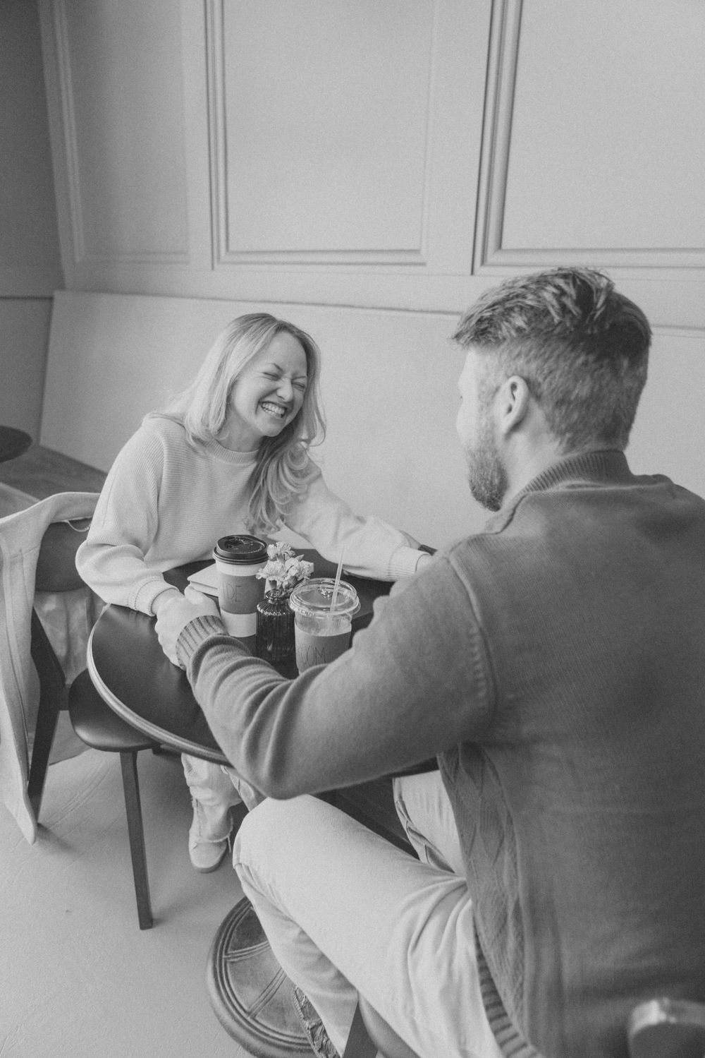 Black and white photo of two people sharing coffee and conversation while sitting together indoors.