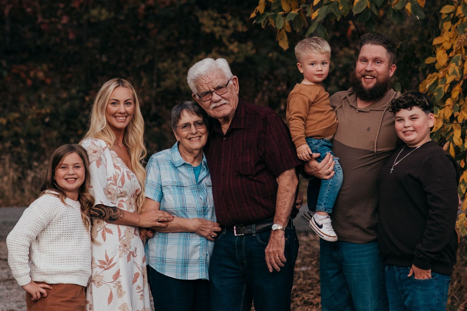 Multi-generational family poses together during an autumn photoshoot outdoors.