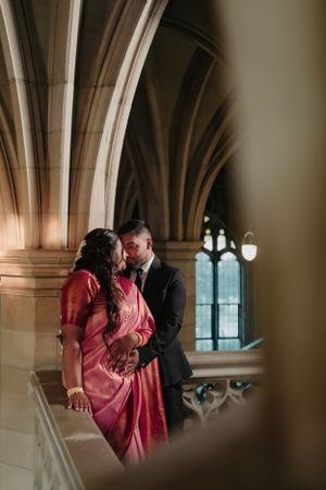 A couple shares an intimate moment among gothic stone arches and pendant lighting.
