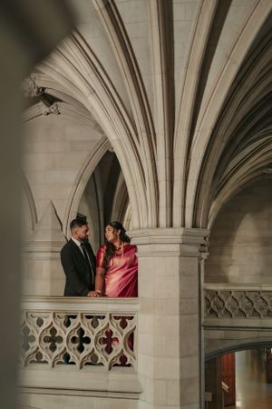 Couple standing beneath dramatic cathedral vaulted ceilings and gothic architecture.